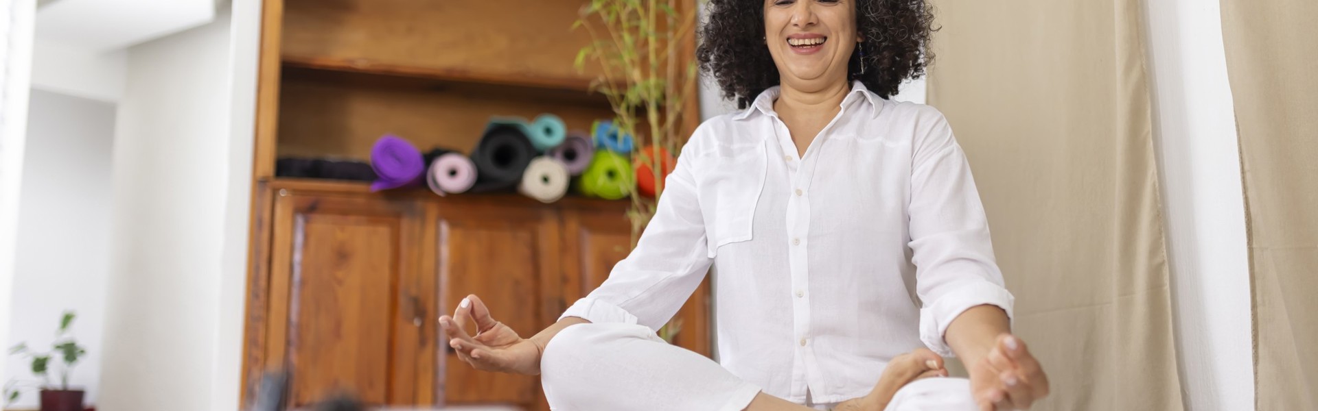 Main image: woman sat at home, taking part in an online meditation or yoga class as part of Mindspace Week!