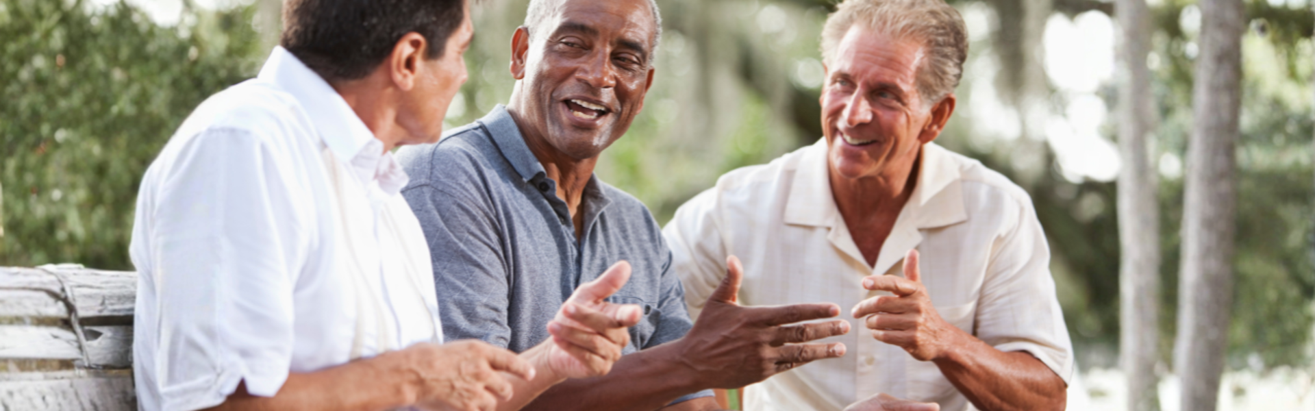 Main image: three men sat on a bench out in nature, smiling, discussing men's health.